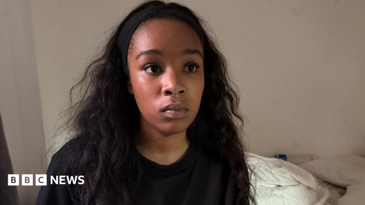 Isabel Rose is seen wearing a black top and a small nose ring, sits facing the camera indoors