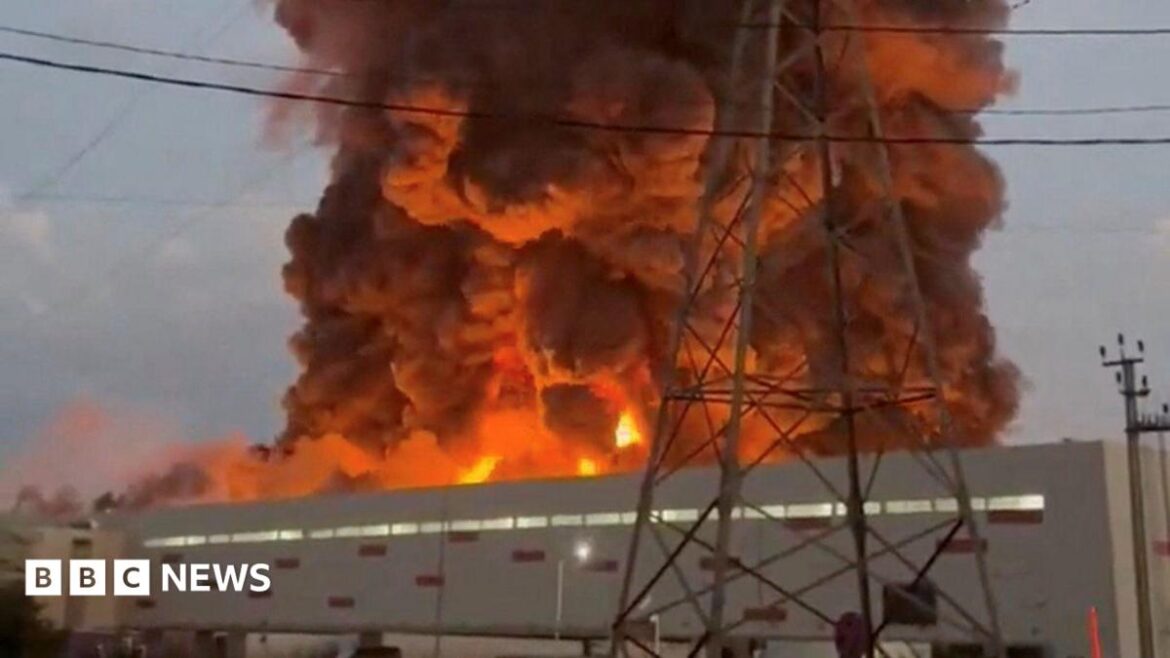 A fire ball rises above a low, light-coloured building