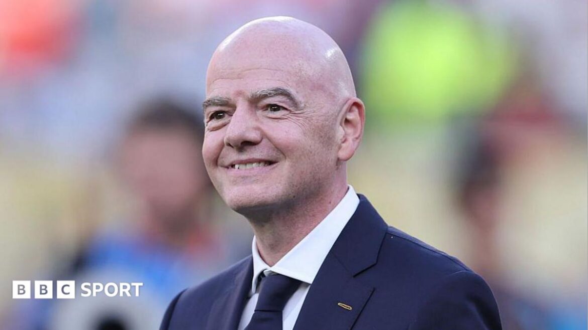 Head and shoulders of a smiling Gianni Infantino, wearing a dark suit and tie
