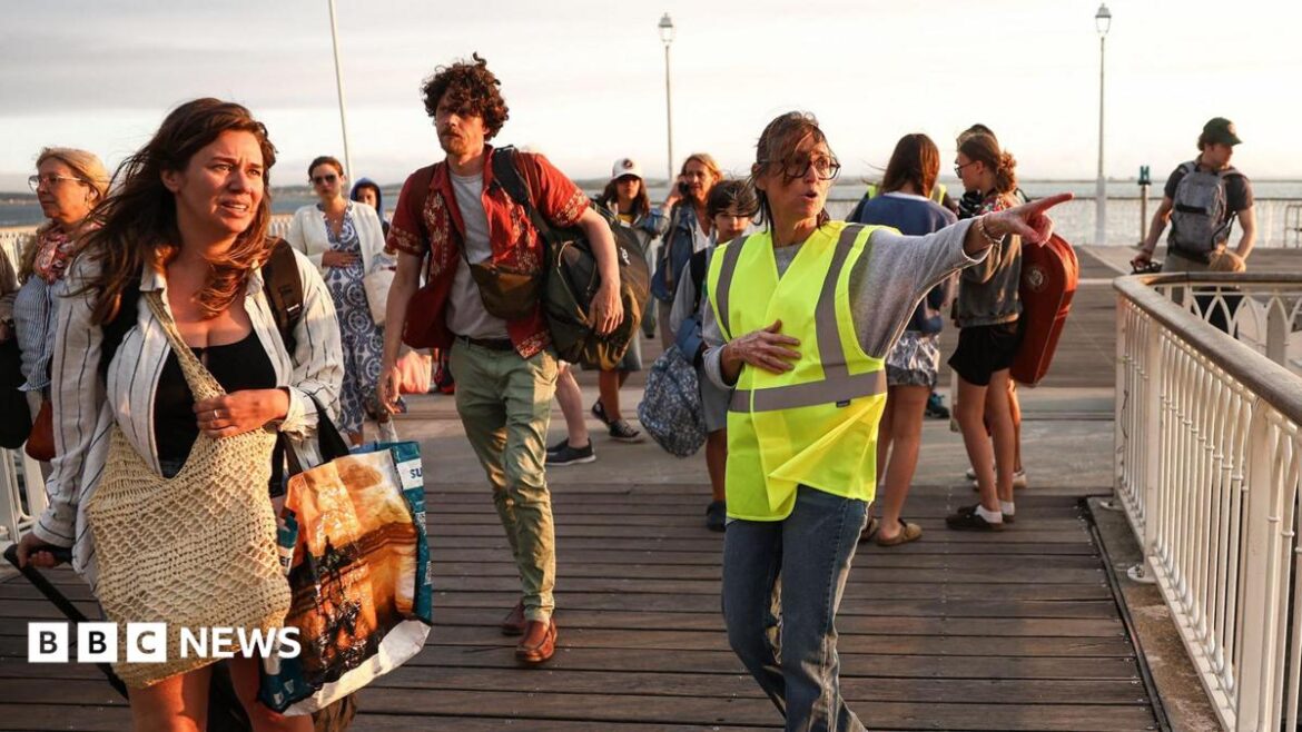 A volunteer gives indication to holidaymakers from Lege-Cap-Ferret upon their arrival in Arcachon by boat during an