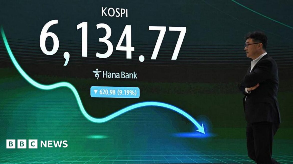 A man walks past an electronic screen showing South Korea's benchmark stock index falling by 9.19%