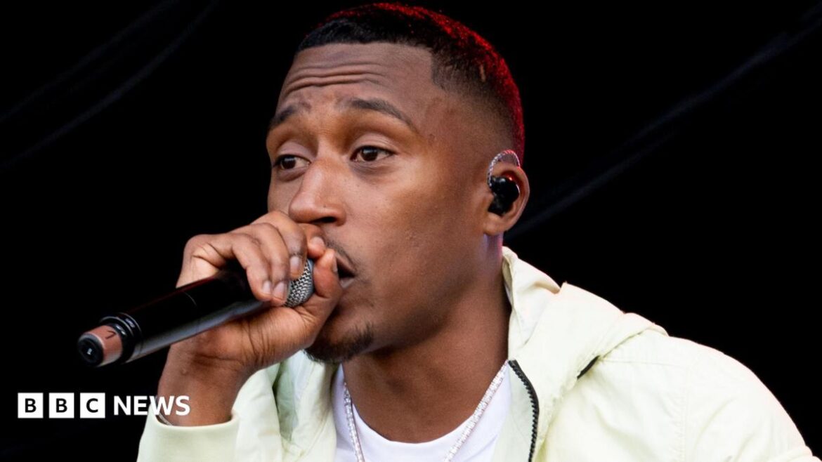 A close up of the rapper Yung Filly on stage holding a microphone to his mouth as he performs