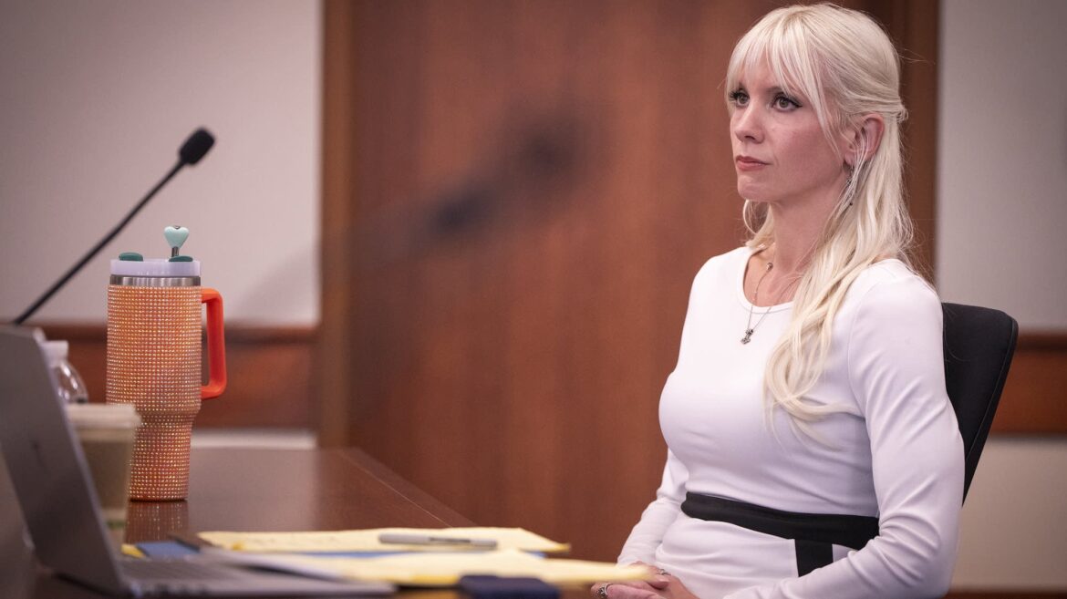 A woman in white sits in a courtroom