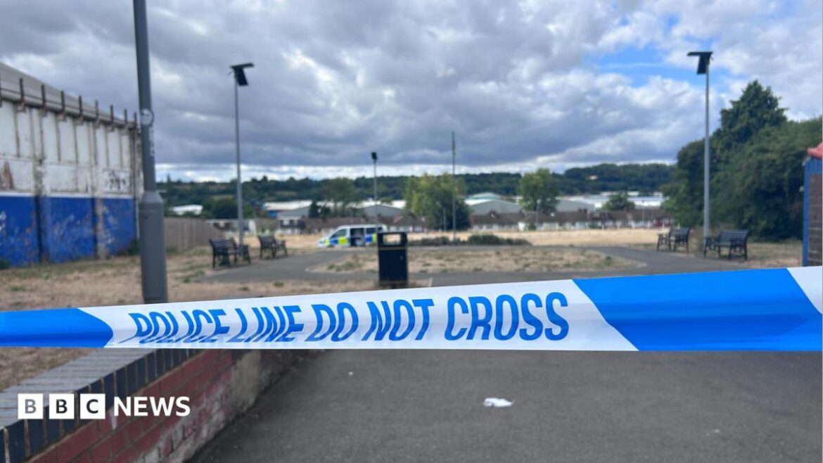 Blue-and-white police tape with the words "Police line do not cross". Beyond the tape, slightly out of focus, there is a
