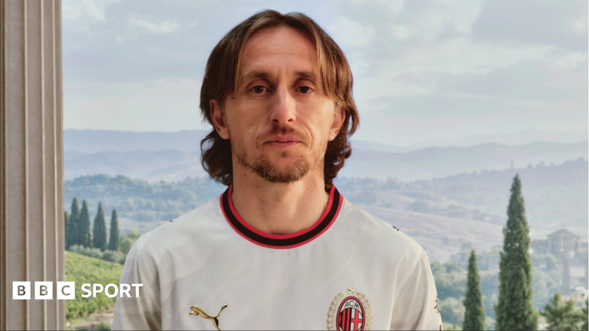 Luka Modric wearing a largely white AC Milan shirt with red and black trim