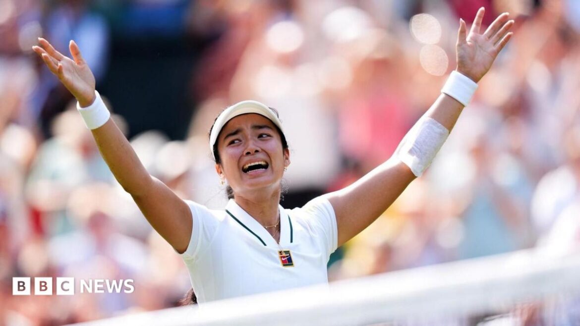 Filipina tennis player Alexandra Eala raises his arms after a Wimbledon match, net in front of her and a blurred image of