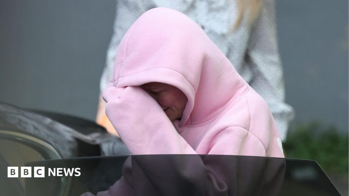 Isobella Perrie Sullivan, a woman wearing a pink hooded jacket, gets into a car following a court appearance. The hood is