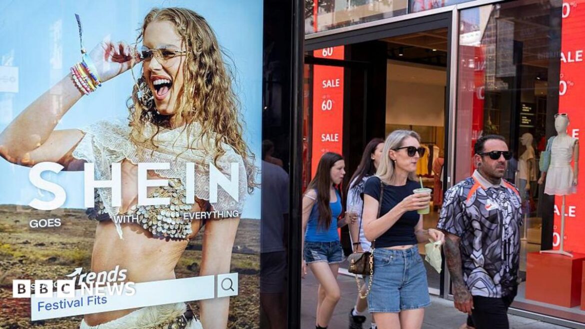 Peolep walking past a bus stop advertising for Chinese e-commerce fashion company Shein on 11 July 2026 in London