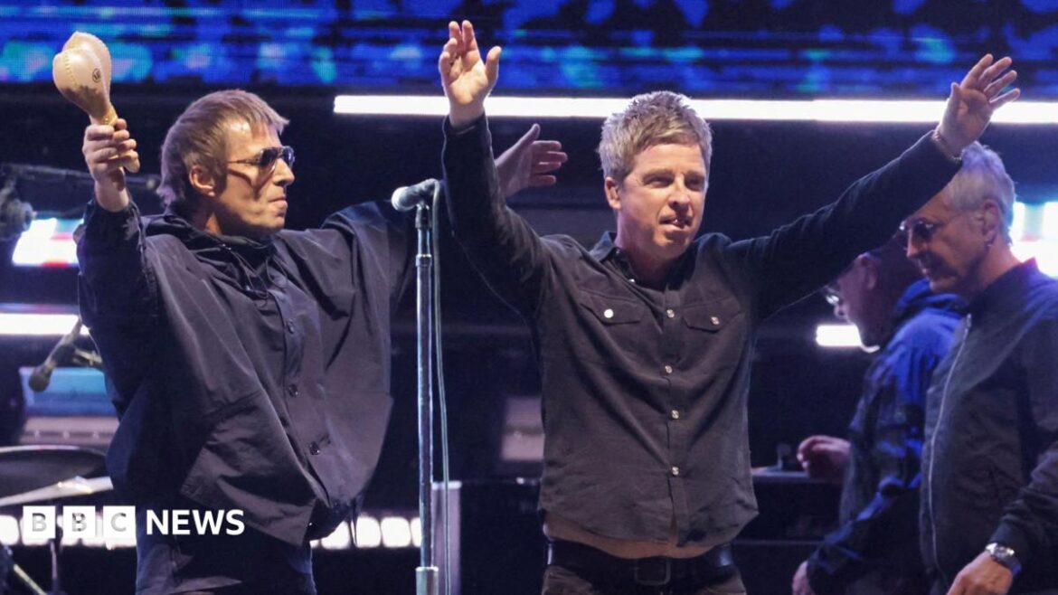 Liam Gallagher and Noel Gallagher of Oasis receive the applause of fans while on stage together at the Rose Bowl Stadium in