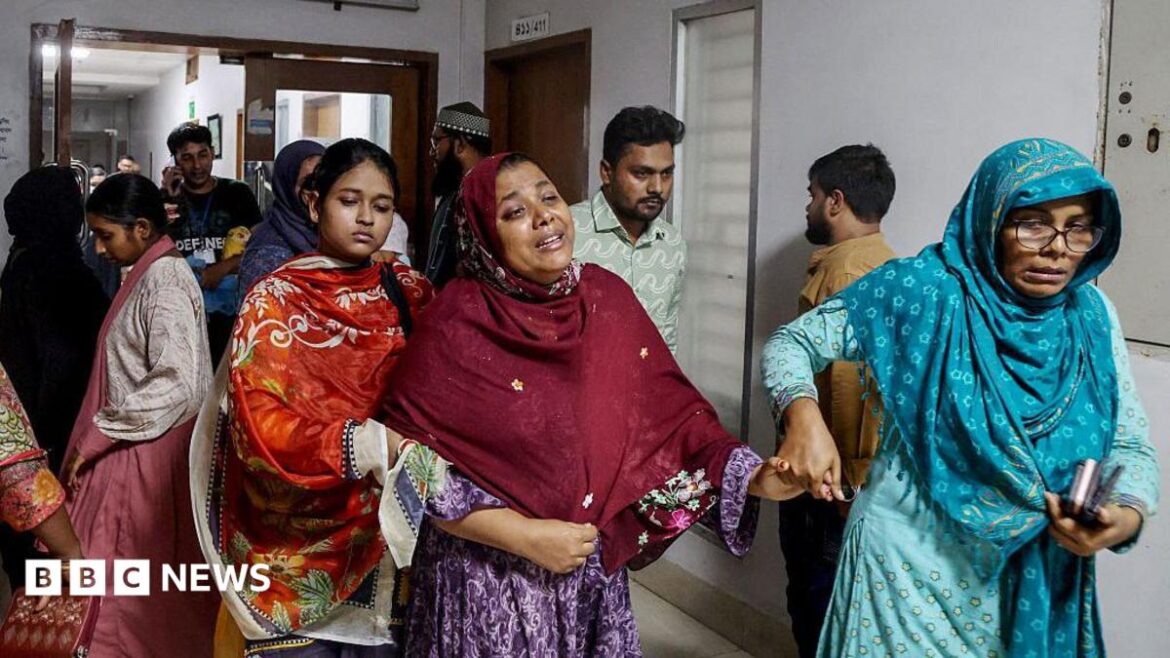 A tearful woman walks along a hospital corridor, held by two other women on both sides