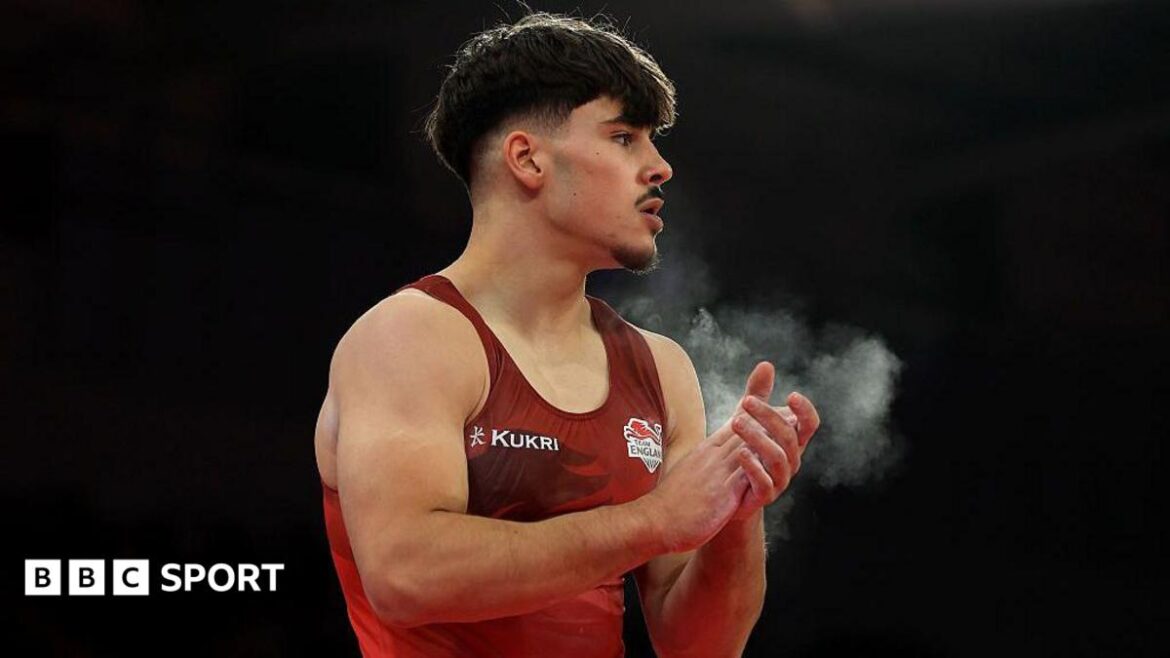 Gabriel Langton claps his hands covered with chalk while wearing a red England vest
