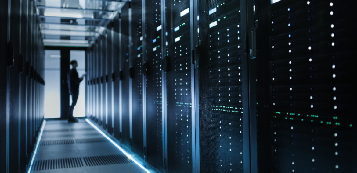 A data center with a worker standing in front of one of the machines