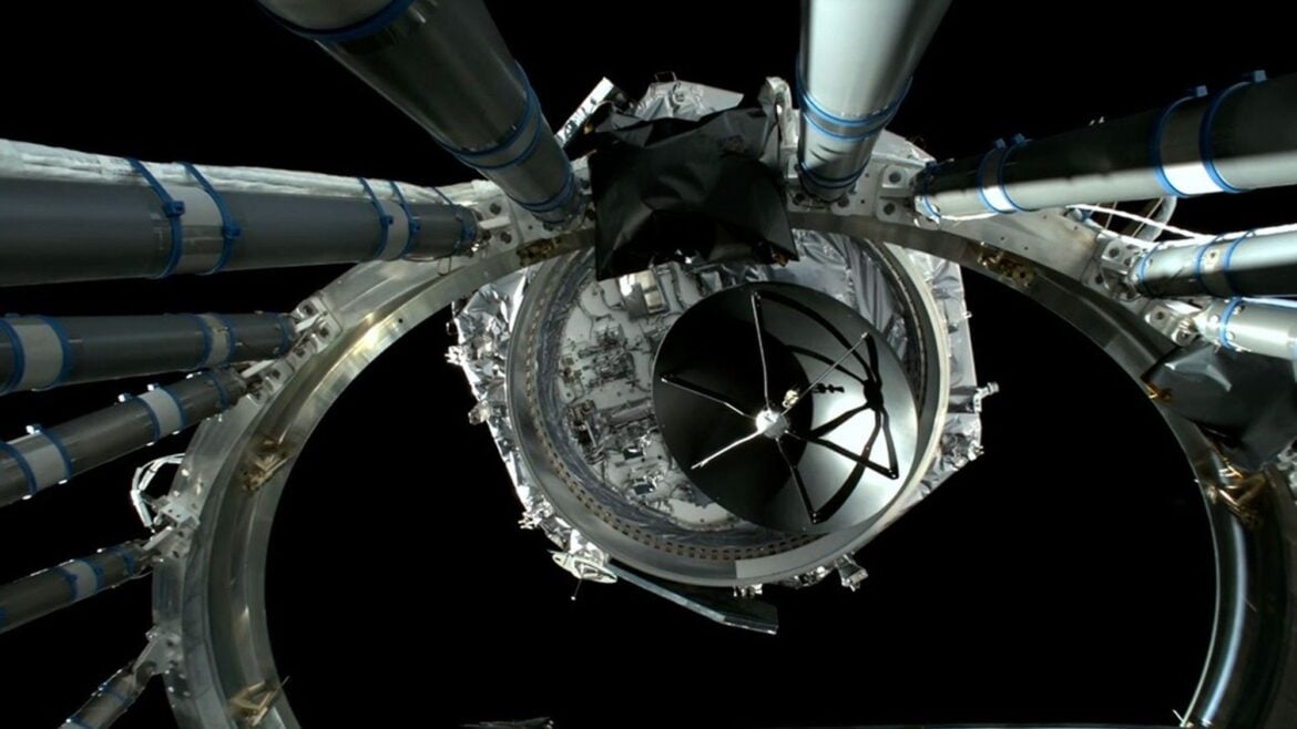 a hexagonal spacecraft floats away from a large metal ring on a black background