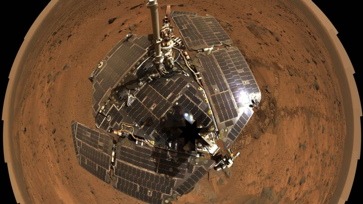 A fisheye view of a solar paneled rover on a reddish terrain