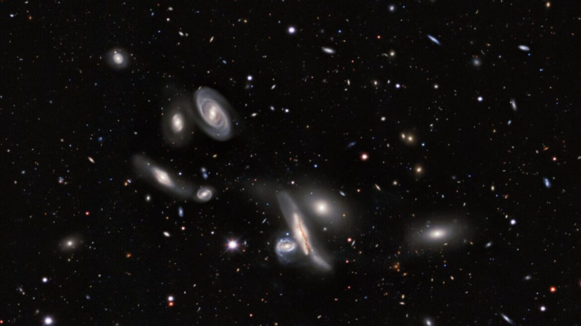 A dark sky speckled with lots of glowing dots. in the foreground, a bunch of hazy blobs of different shapes and sizes
