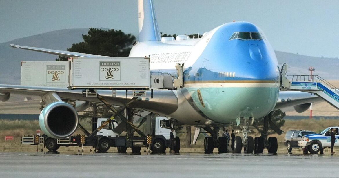 Catering trucks are parked at Air Force One on the tarmac as the motorcade carrying U.S. President Donald Trump arrives on