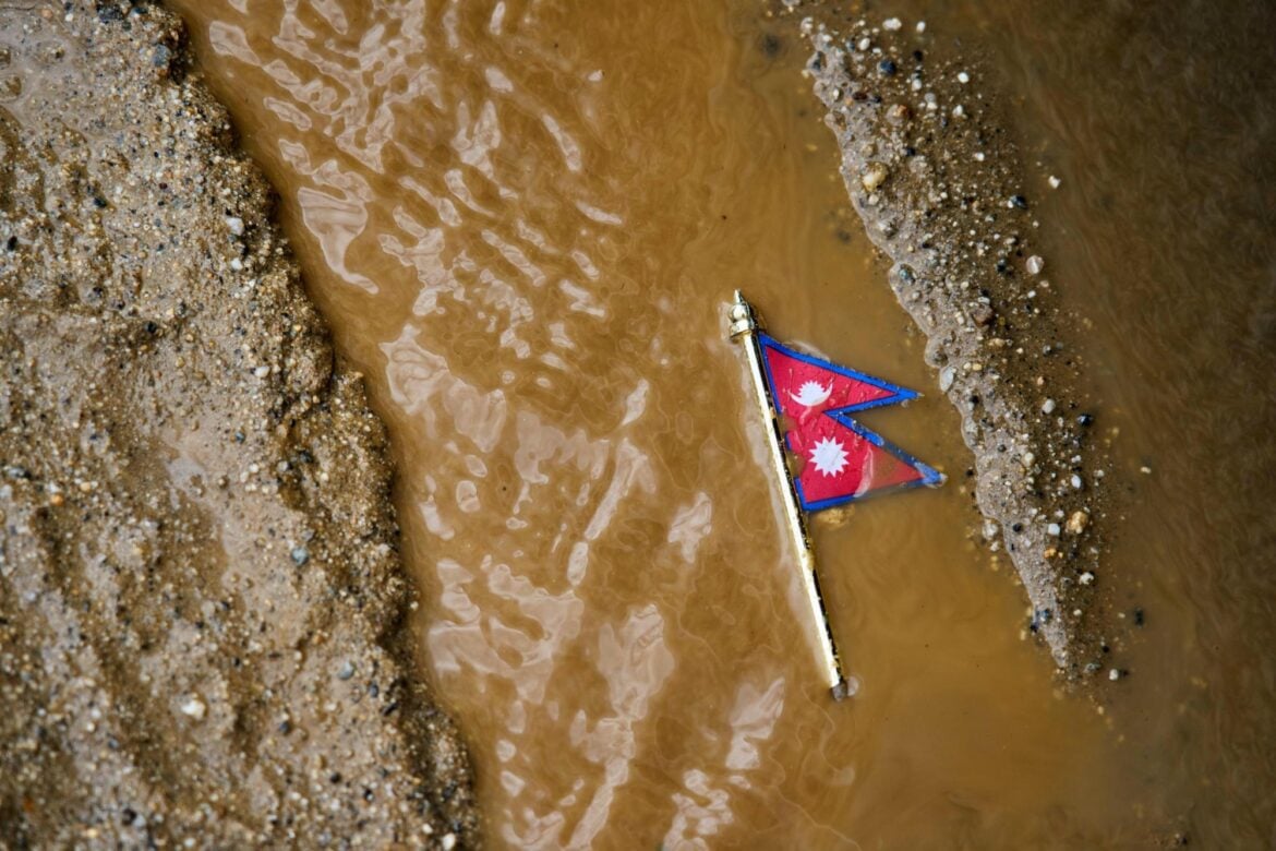 A Nepal flag lies on a muddy track near the banks of the Trishuli river