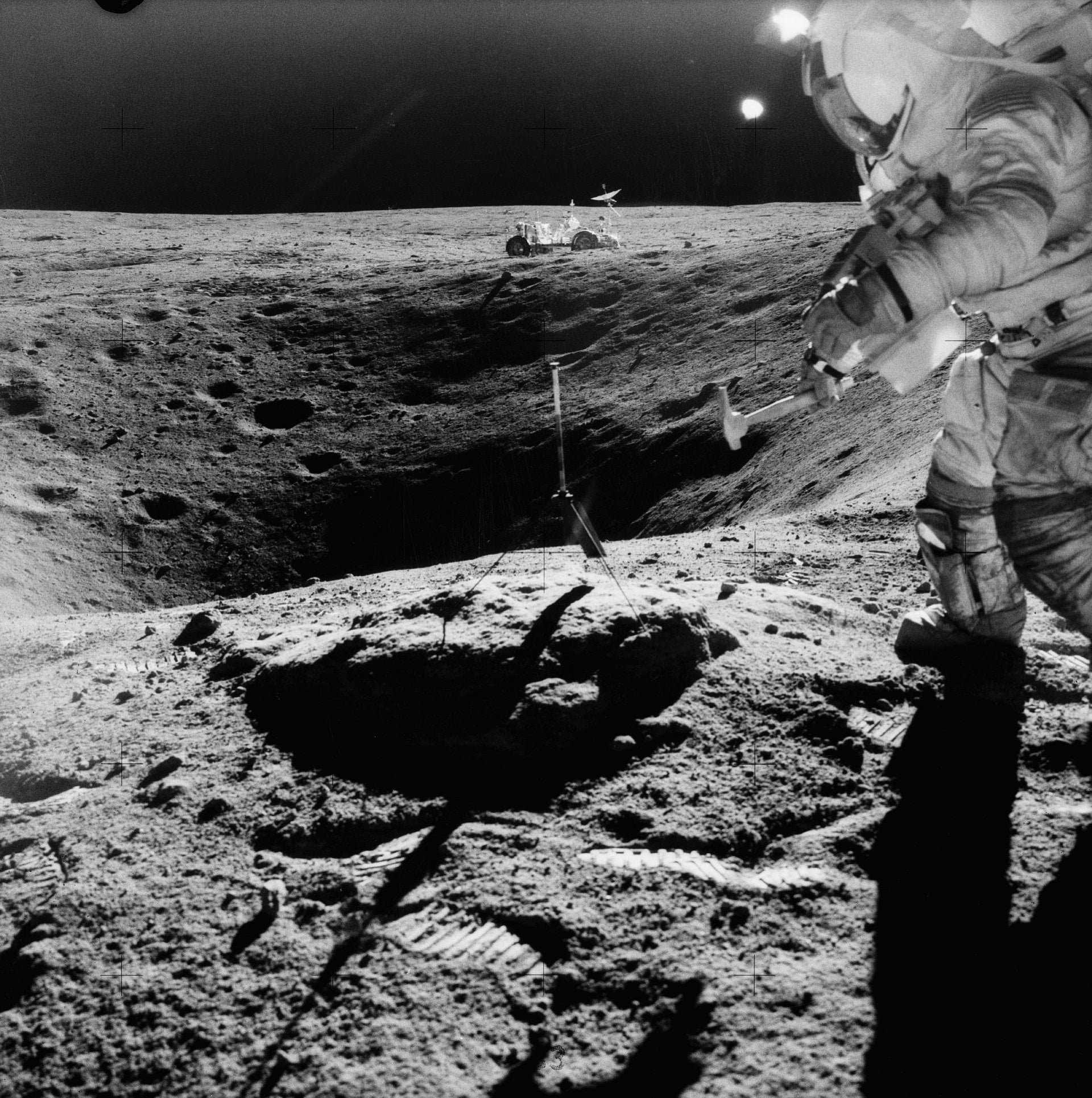 Astronaut John W. Young, commander of the Apollo 16 lunar landing mission, stands on the rim of Plum Crater while collecting
