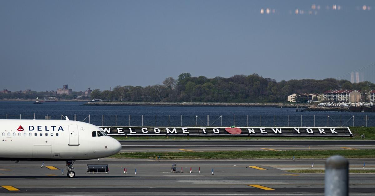 A Delta Airlines Airbus A321 plane passes by a "Welcome to New York" sign along the runway at LaGuardia Airport (LGA) on