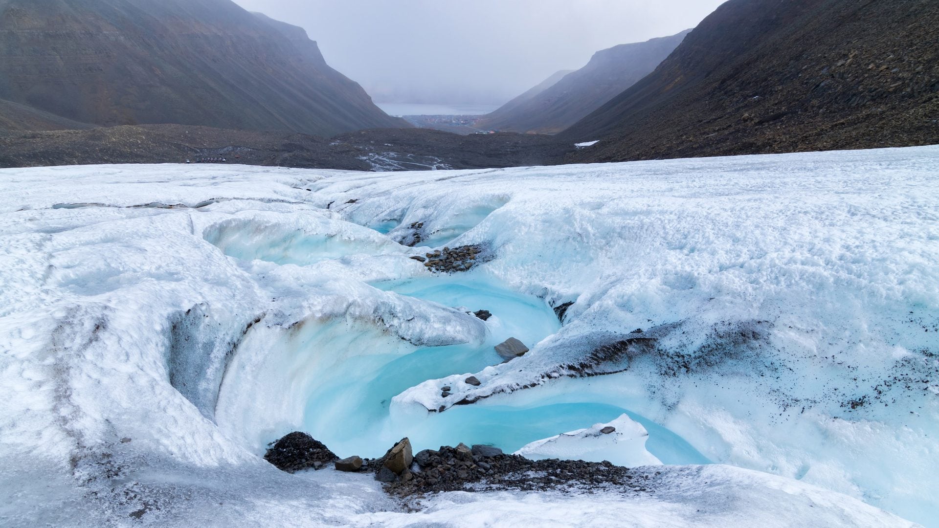 Bright blue meltwater winds through channels in a glacier on Svalbard, Norway