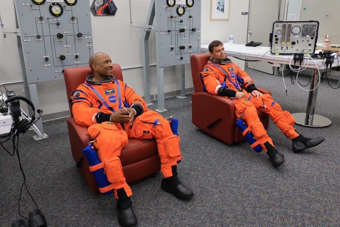 From left, NASA astronauts Victor Glover, Artemis II pilot and Reid Wiseman, Artemis II commander, are seated in chairs