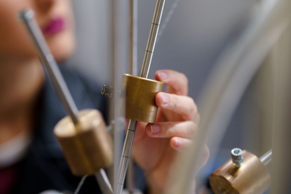 A person adjusts brass components in a physics experiment