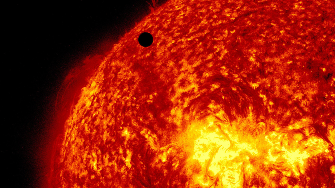 A black object behind the fiery red planet of Venus