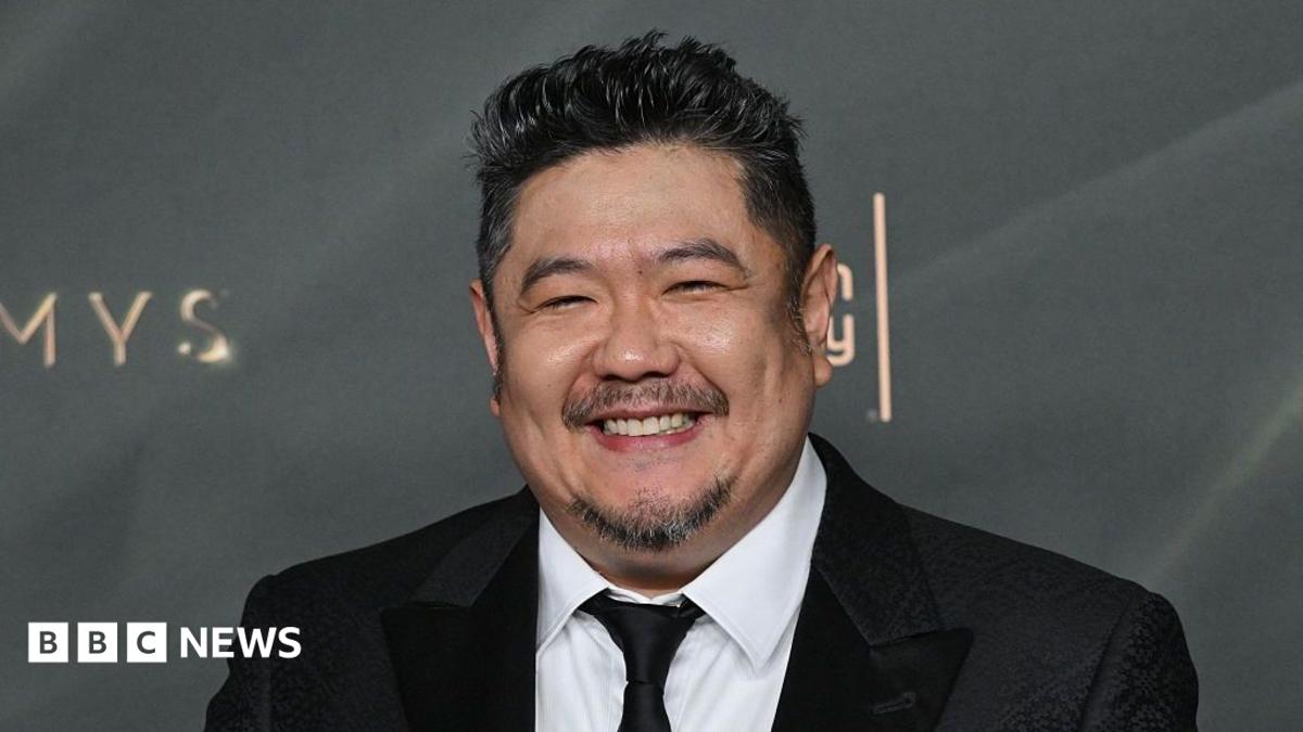 A man in a dark suit with a close-cropped goatee smiles at a premiere