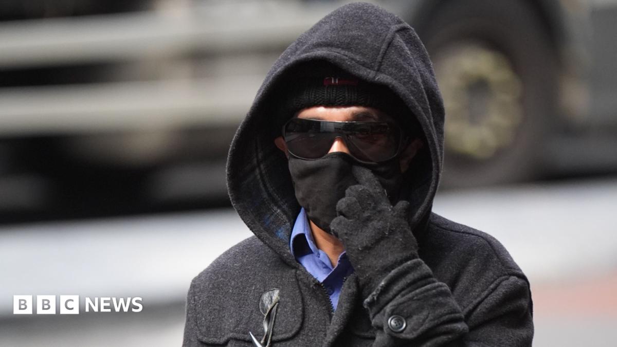 A 55-year-old man wears sunglasses, a hat, hood and gloves as he arrives at court