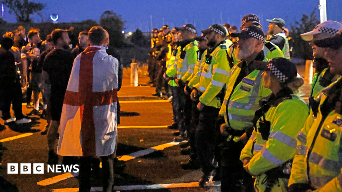 There is a line of police to the right of the image, facing towards the left. They're wearing yellow hi-vis jackets and