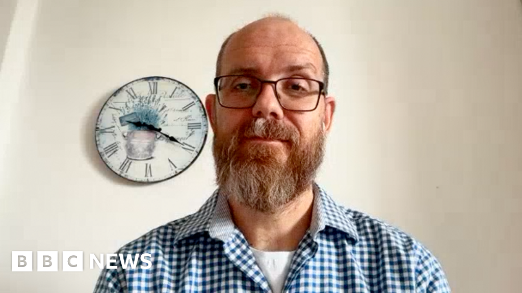 Ondřej Surý looking towards the viewer with a calm expression. He is bald with a beard and wears glasses. He is wearing a