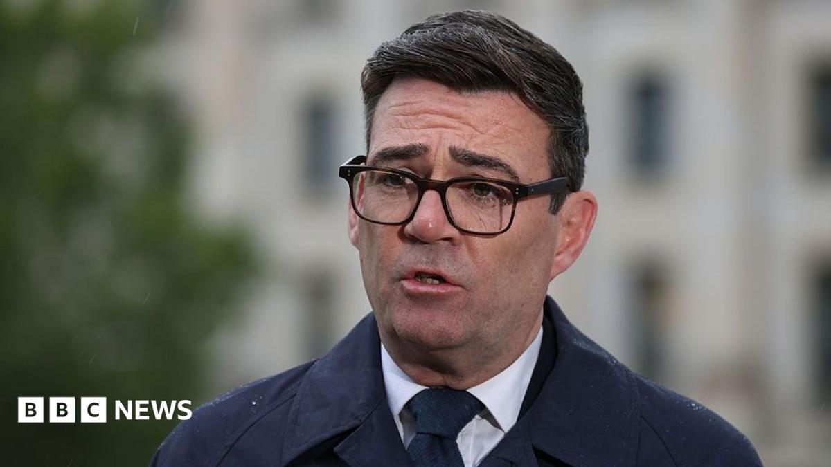 Andy Burnham, wearing a dark suit, recording a media interview in Berlin