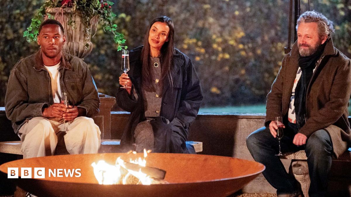King Kenny, Mya and Michael Sheen sit tentatively around the firepit on the penultimate night of The Traitors