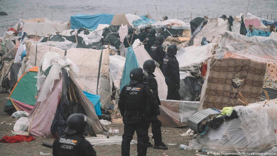 Police stand among makeshift tents in temporary migrant camps in Ceuta