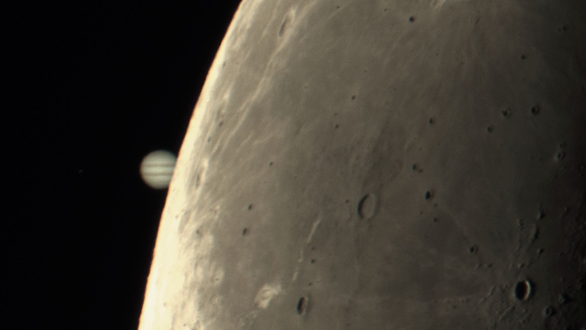 Jupiter is shown partially occulted by the lunar disk in a black sky