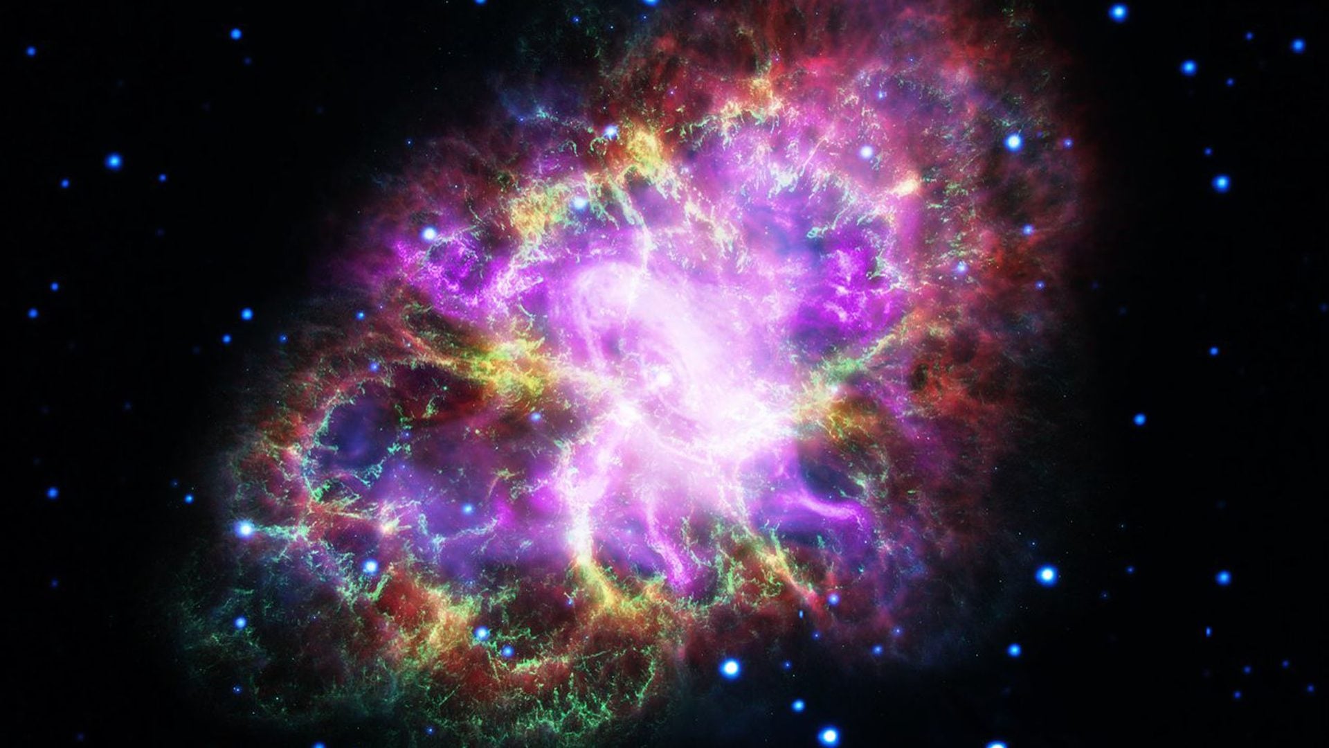 A colorful composite image shows the Crab Nebula, the remains of a supernova explosion about 6,500 light-years from Earth