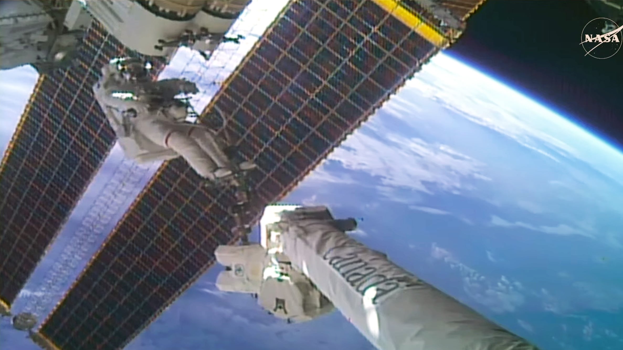 NASA astronaut Anil Menon rides the Canadarm2 robotic arm to begin the installation of a roll-out solar array on the
