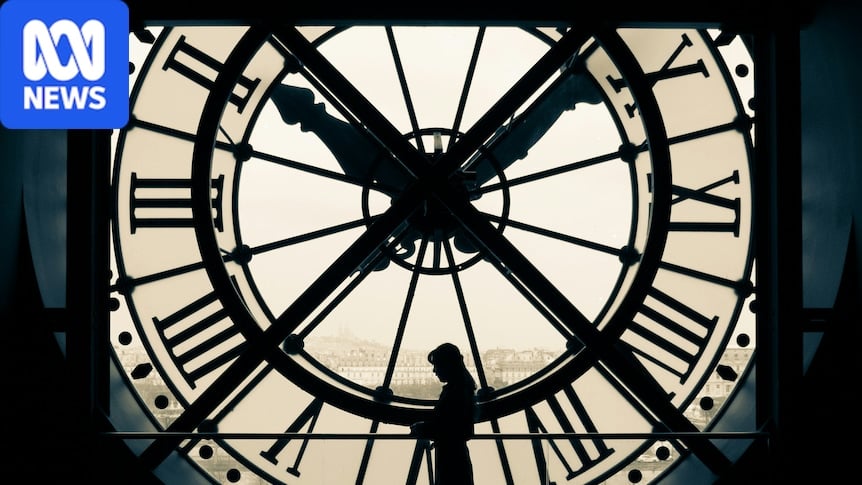 Silhouette of a person standing against a large wall clock