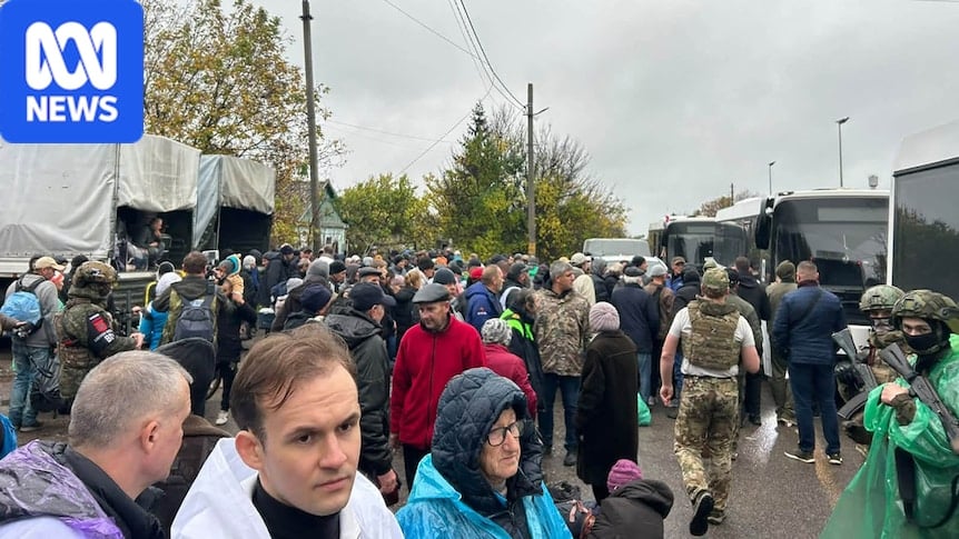 People in winter clothes prepare to board buses on a dreary day