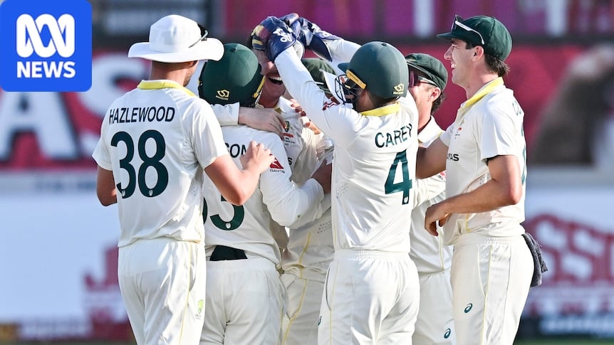 A group of cricketers celebrate a wicket with a group hug