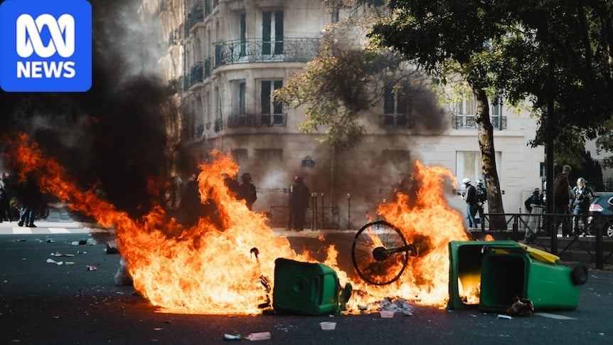 Bins on fire in front of a building