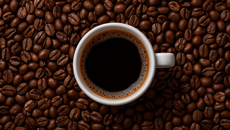 a cup of black coffee sitting on a bed of coffee beans