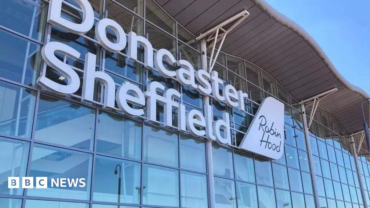 A wall made up of dozens of windows has large white lettering which says Doncaster Sheffield. There is a sign which looks